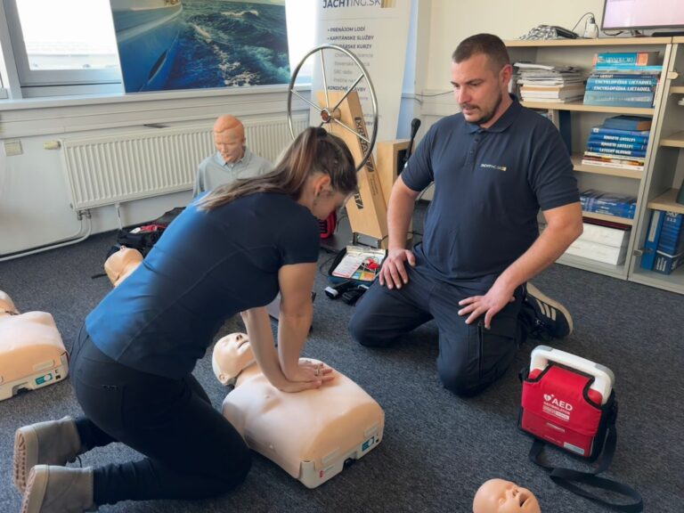 Účastníčka kurzu cvičí KPR pod dohľadom inštruktora s AED defibrilátorom
